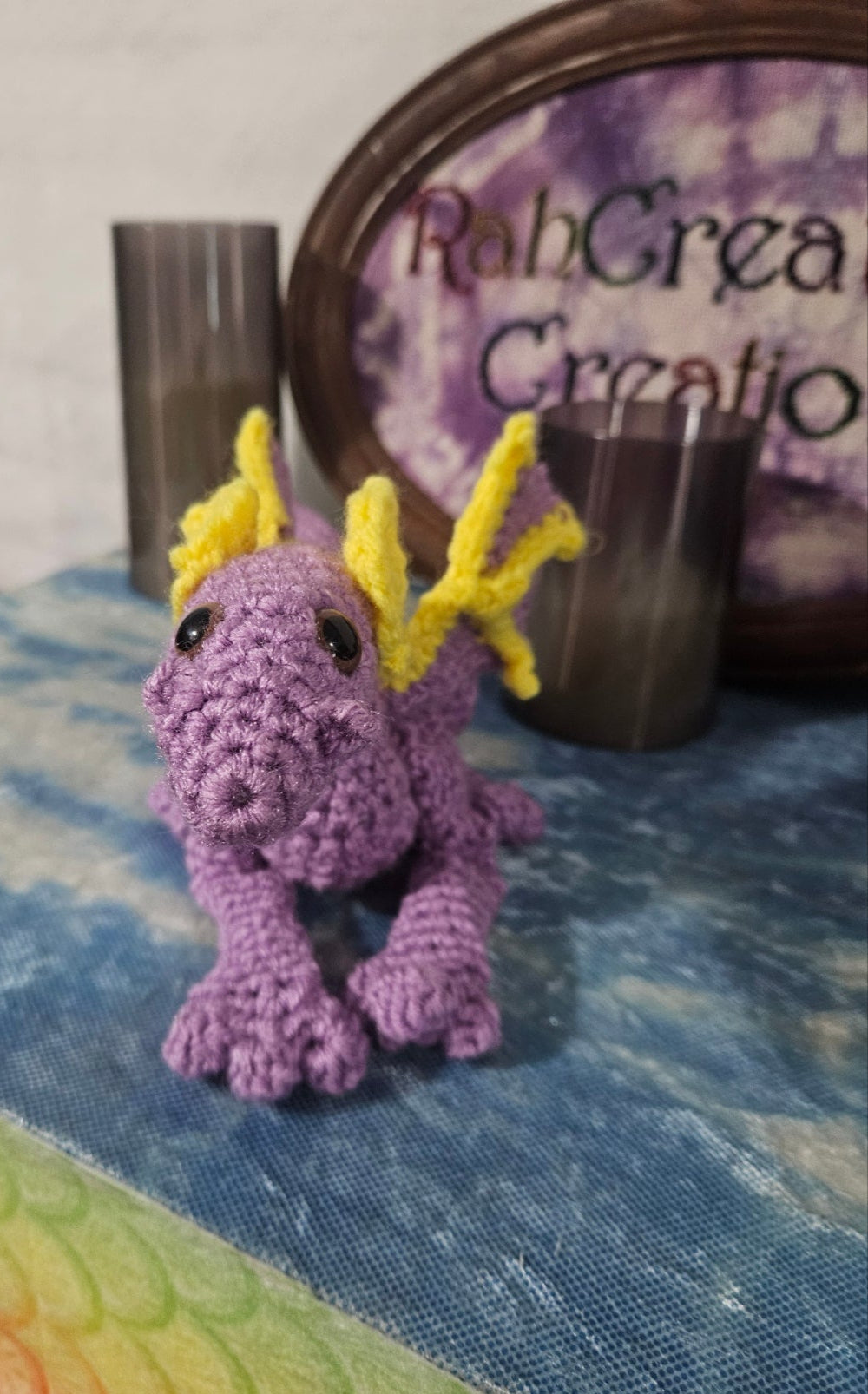 Purple crocheted dragon toy with yellow spikes on a textured surface