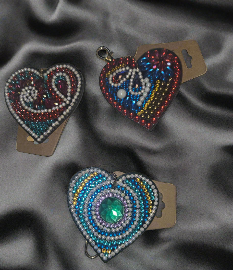 Three beaded heart-shaped earrings on cardboard backing against a light background