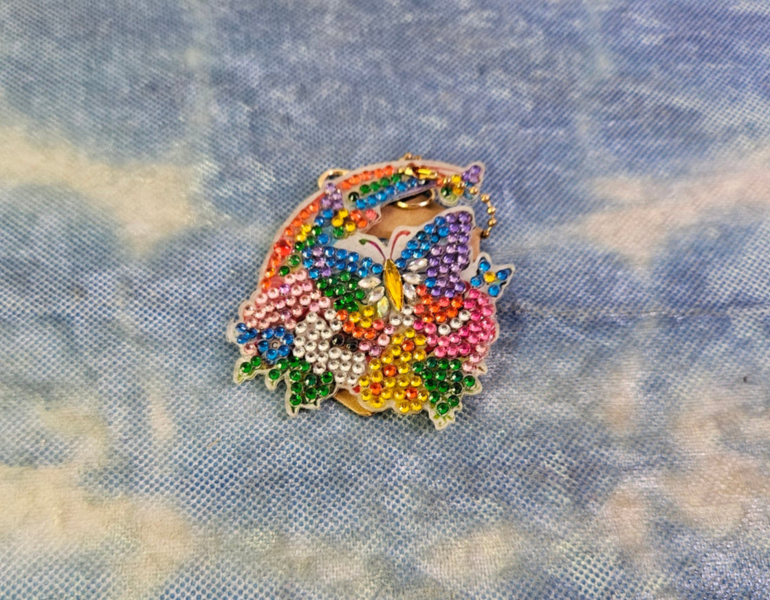 Colorful beaded butterfly pin on a denim fabric background