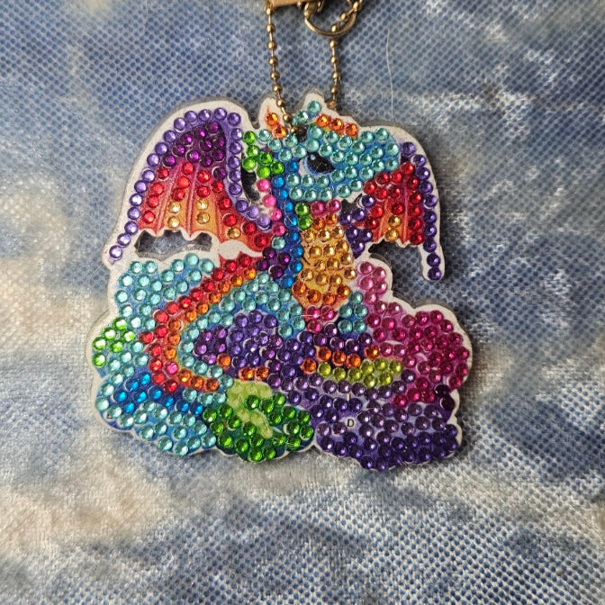 Colorful beaded dragon keychain on a textured fabric background