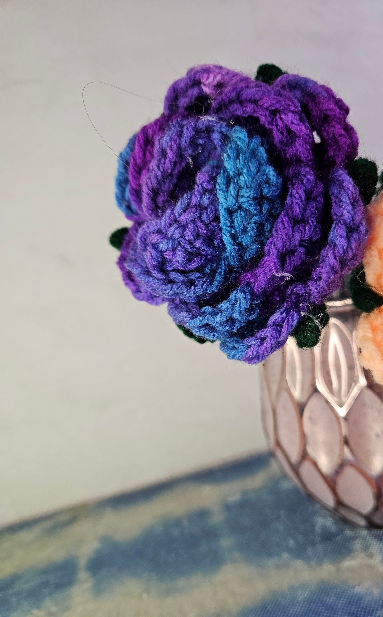 Crocheted purple flower on a small plush toy with a neutral background