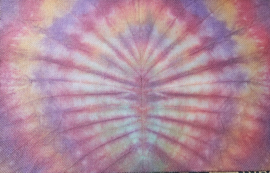A square fabric textile with a vibrant tie-dye spiral pattern in pink, purple, orange, and white, laid flat on a patterned fabric background.