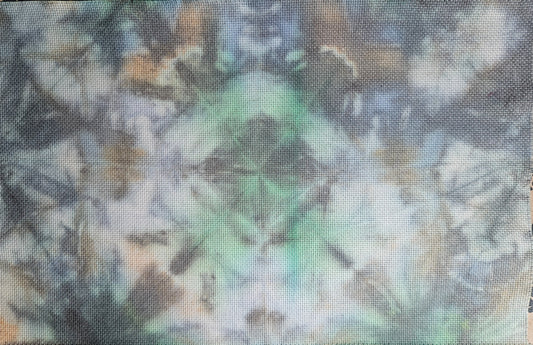 A square woven textile with an abstract tie-dye pattern in shades of green, gray, blue, and beige, laid flat on a patterned beige surface.